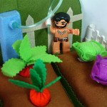 Close up view of a child's pretend vegetable garden, constructed of felt plants and vegetables.