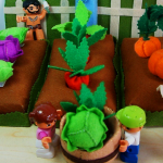 A child's vegetable garden constructed with felt vegetables and plants.