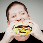 Man eats a huge cheeseburger: a common block to low carb diet success.